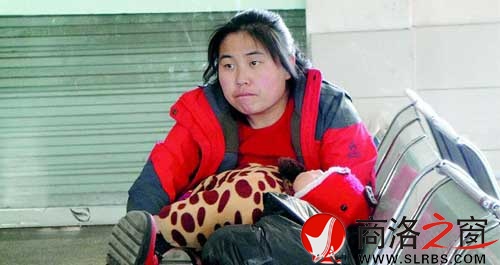 候車廳里，一位母親抱著睡著的孩子發(fā)呆